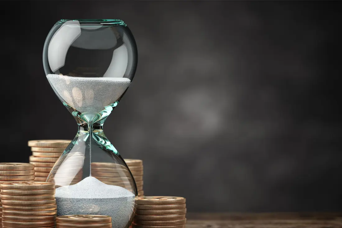 An hourglass among stacked coins: months of trading, and what they added up to.